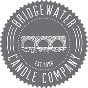 Gray circular logo with a white illustration of a stone bridge over water in the center. Text around the edge reads Bridgewater Candle Company and Est. 1998 below the bridge.