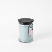 The Bridgewater Candle Company Salt & Sea Glass 18 oz Large Jar Candle features light blue soy-blend wax in a clear glass jar with a black wooden lid, plus a seashell tag and branding, shown against a plain white background.