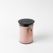 The Bridgewater Candle Sunkissed 18oz Large Jar Candle features a pink soy-blend wax in a clear glass jar with black lid and label, plus a small tag. Enjoy the refreshing Sunkissed scent against a plain white background.