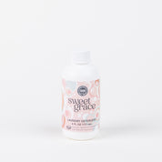 A 6oz bottle of Bridgewater Candle Companys Sweet Grace Laundry Detergent, with a pink and white circular label, stands upright against a plain white background. This fabric-safe detergent provides a long-lasting scent.