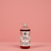 A clear plastic bottle of Sweet Grace Flower Diffuser & Refill Bundle by Fast Bundle, filled with pink liquid, makes a perfect fragrance gift and is shown against a solid pink background.
