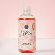 A clear 16 FL OZ (473 mL) bottle of Bridgewater Candle Sweet Grace Bubble Bath with a label featuring pink and grey concentric circles.