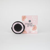 The Bridgewater Candle Company Bridgewater + Pura Car Diffuser Cartridge Sweet Grace, in black and pink, sits beside its matching abstract-patterned pink box on a white background.