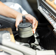 Person putting a Pura Car diffuser device inside the cup holder of their car.
