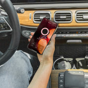 A person seated in a car uses a smartphone with a voice recording app, while a Bridgewater Candle Company Bridgewater + PURA Sweet Grace Car Diffuser Set is clipped to the modern wooden dashboard vent.