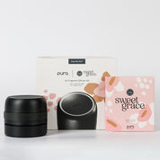 A Bridgewater + PURA Sweet Grace Car PRO Diffuser Set by Bridgewater Candle is shown with the black diffuser in front of its white branded box, next to a pink Sweet Grace refill box, offering a long-lasting car fragrance experience.