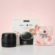 The Bridgewater + PURA Sweet Grace Car PRO Diffuser Set by Bridgewater Candle includes a sleek black diffuser, floral and refill boxes, all on a light pink background. Enjoy a long-lasting car fragrance wherever you go.
