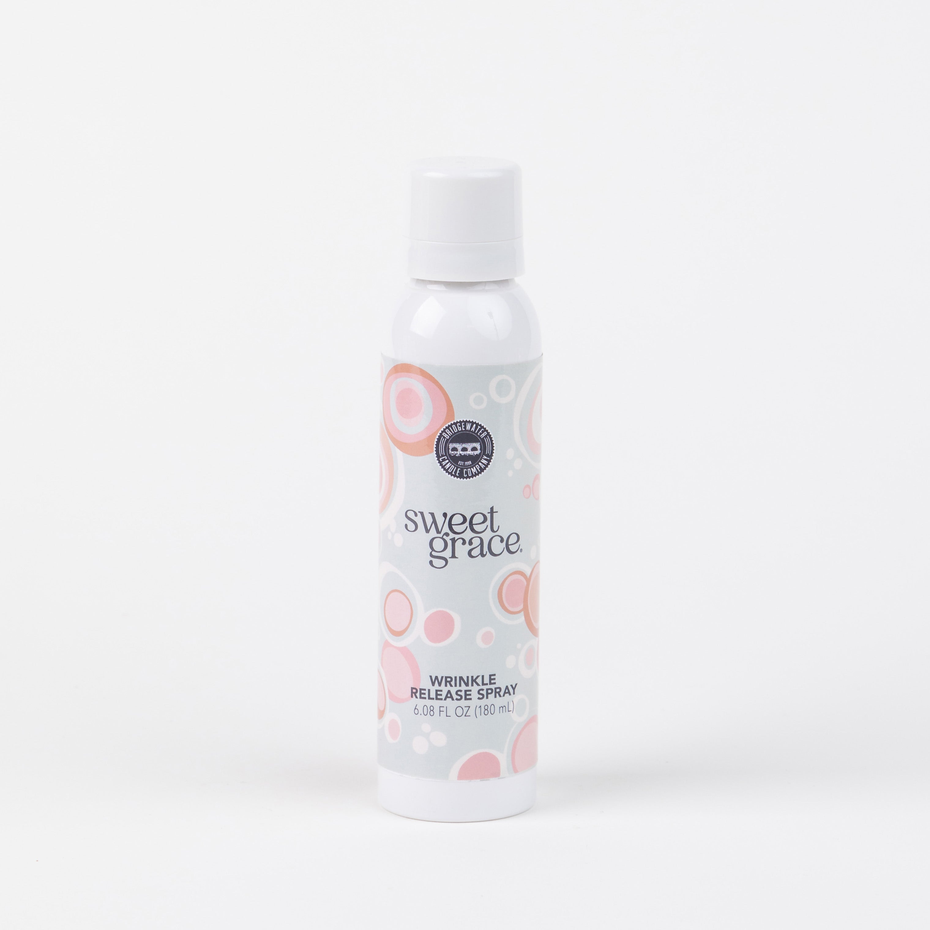 A white spray bottle labeled Sweet Grace Wrinkle Release Spray by Bridgewater Candle Company features pink and beige circles and stands upright on a white background—ideal for refreshing clothes.
