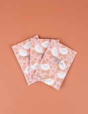 Three Sweet Grace Modern Flower Sachets by Bridgewater Candle Company are arranged in a fan shape on a peach background. Their pink and white abstract flower designs add a fresh home fragrance to any space.