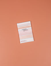 The Bridgewater Candle Company Sweet Grace Modern Stripe Sachet, featuring a pink and white striped design, rests on a peach surface—ideal for infusing your space with home fragrance.