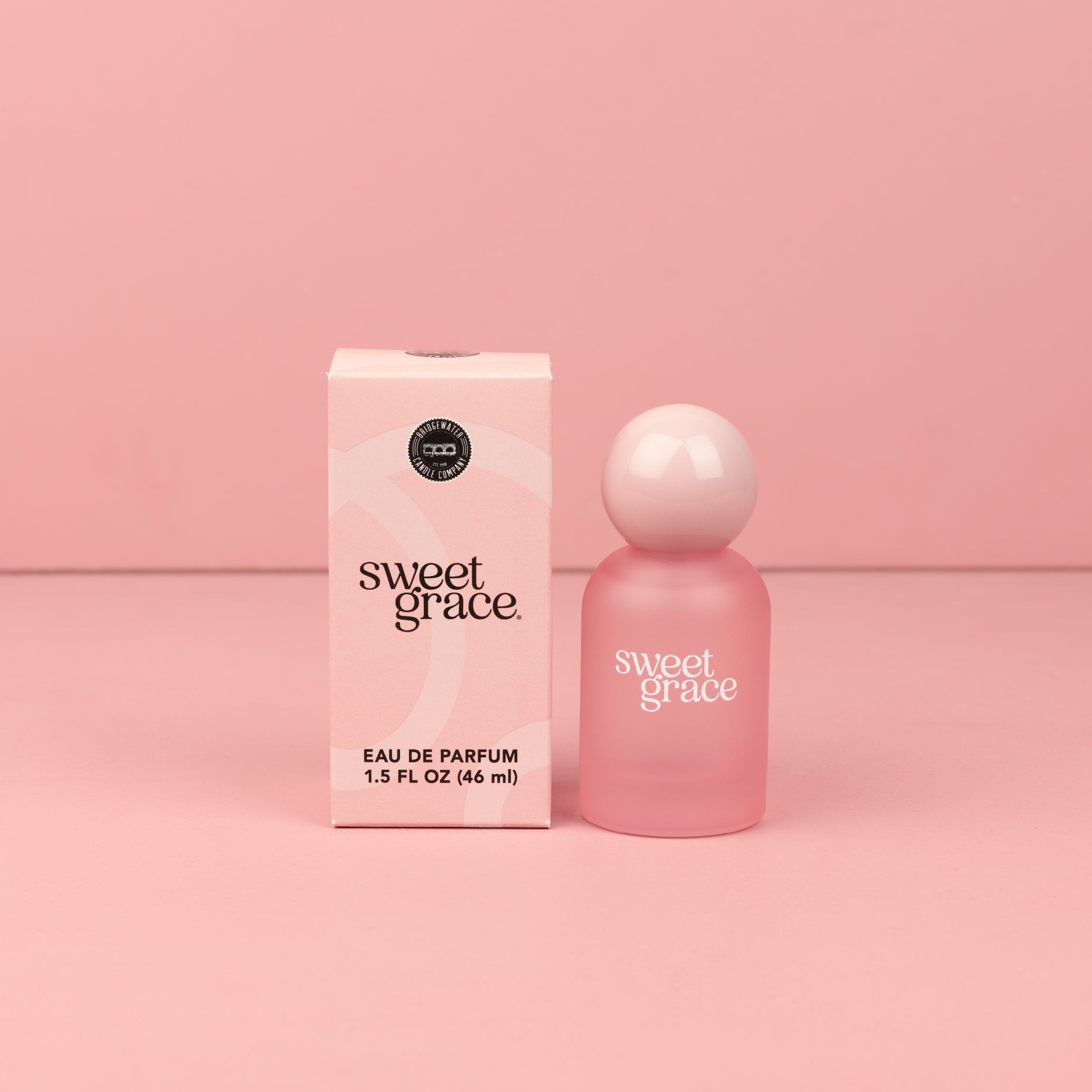 A Sweet Grace Eau de parfum box and frosted pink Sweet Grace eau de parfum bottle with pink round ball cap on pink background