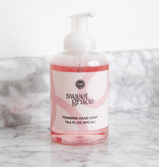 A clear pump bottle of Bridgewater Candle Company’s Sweet Grace Foaming Hand Soap sits on a marble countertop, featuring an oriental scent, moisturizing aloe, and a 16.6 fl oz (490 ml) label.