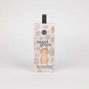 The Bridgewater Candle Sweet Grace Body Wash Sponge, 3.5 oz (100 g), features a pink and brown bubble design with a black hanging ribbon, delivering creamy lather and gentle exfoliation, shown on a white background.