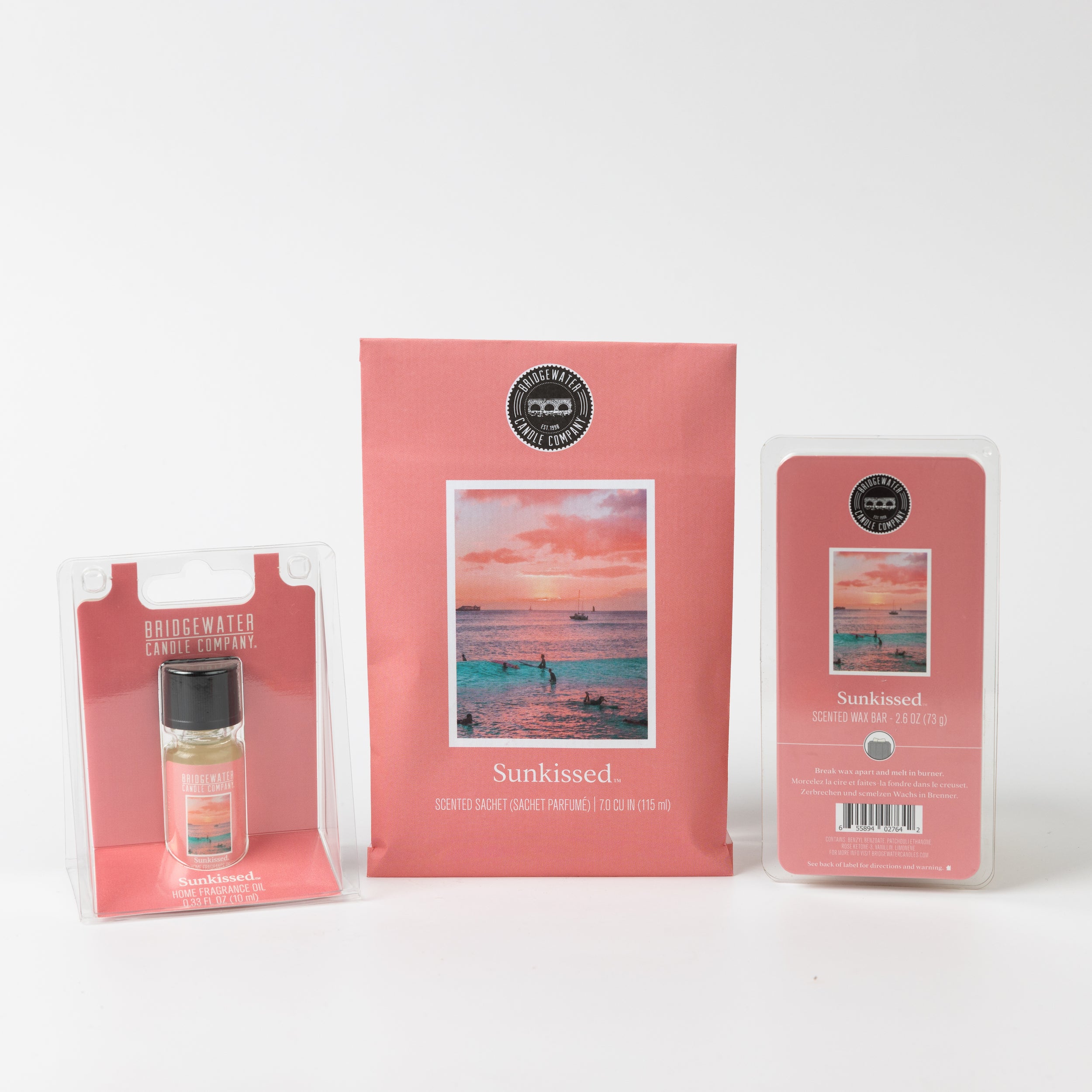 The Sunkissed Flameless Bundle by Bridgewater Candle includes three upright products, each with a pink label featuring a sunset beach scene and the Bridgewater Candle logo above the product name.