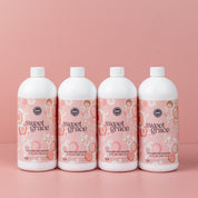 Four bottles from the Fast Bundle Back to School Laundry Bundle 4pk, each featuring pink and orange bubble designs on the label, are lined up in front of a plain pink background—perfect for those who love fresh-smelling laundry with a touch of elegance.