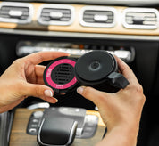 Person holding a Let's Celebrate pura car refill and pura car device inside the front of a car's interior.