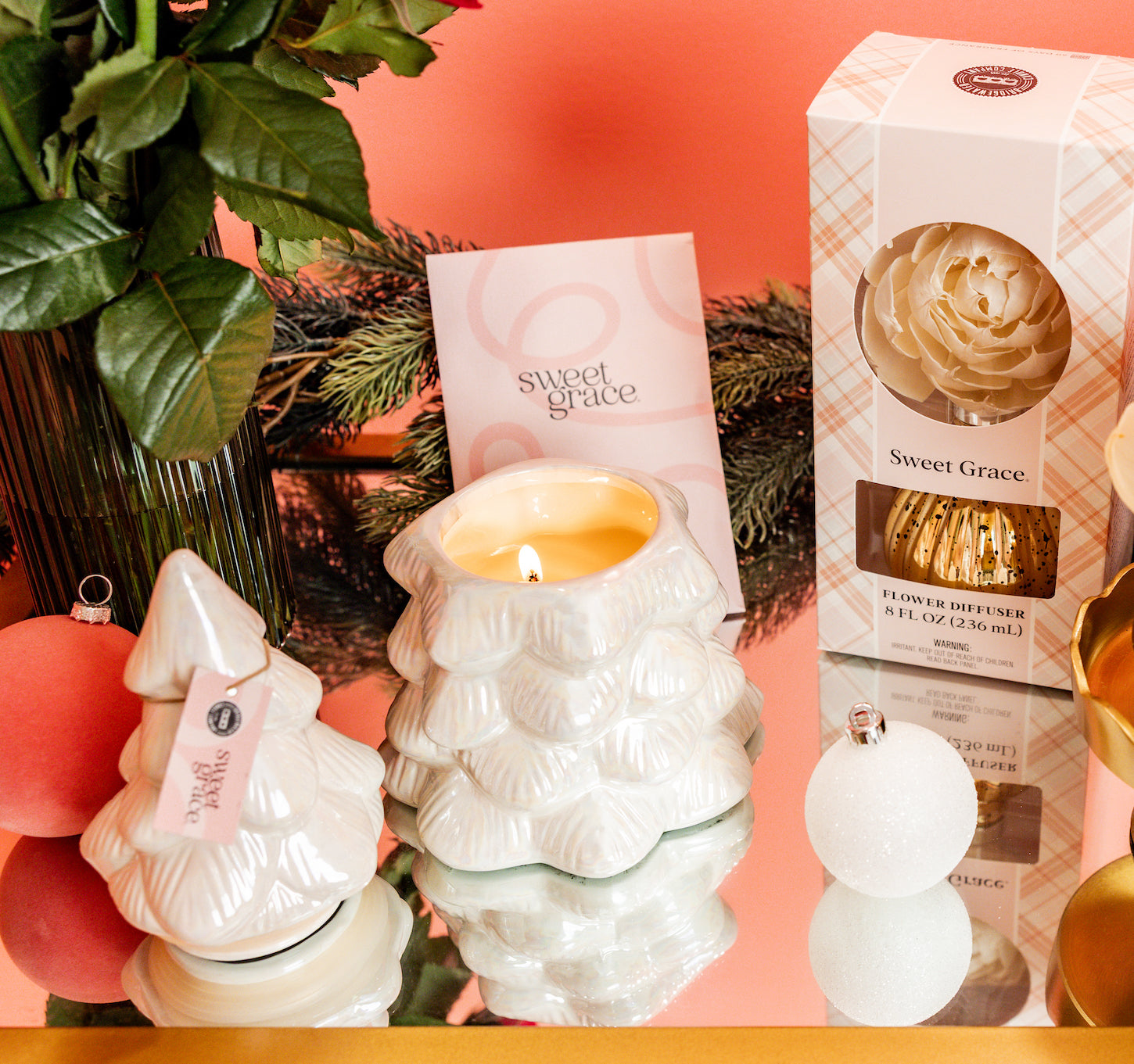 The Bridgewater Candle Sweet Grace Collection Candle #70 in a white ceramic holder sits on a table with festive décor, creating a charming holiday centerpiece.