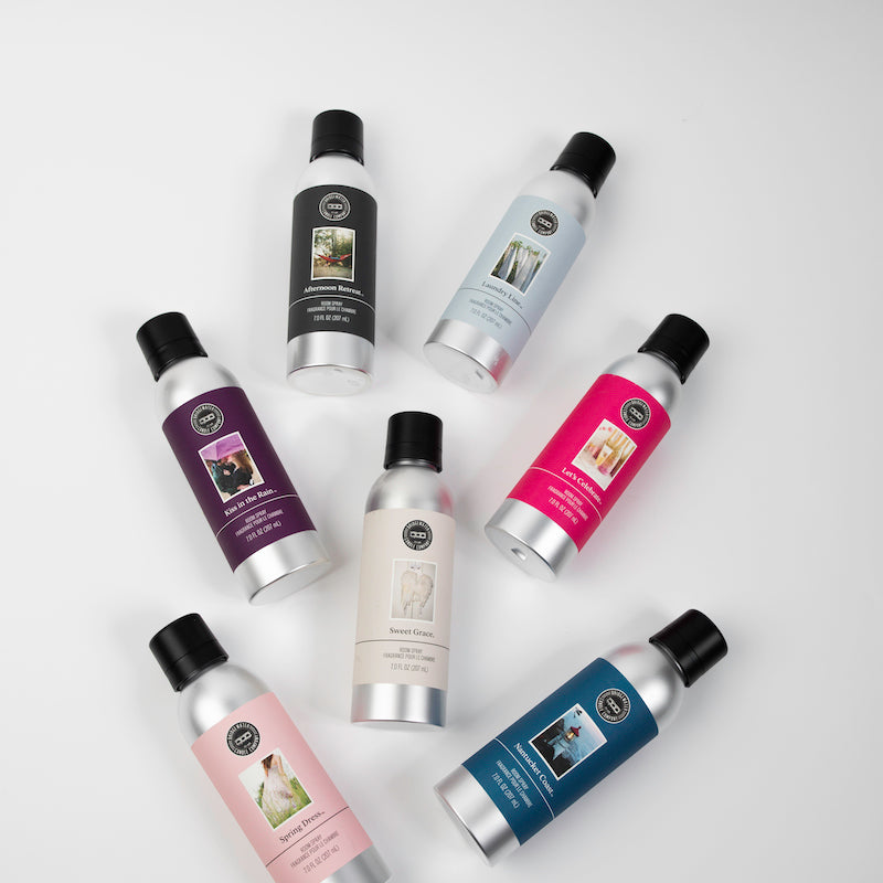 Seven metallic bottles with black caps, each labeled with different colors and images of animals, are arranged in a loose circular pattern on a plain white background.