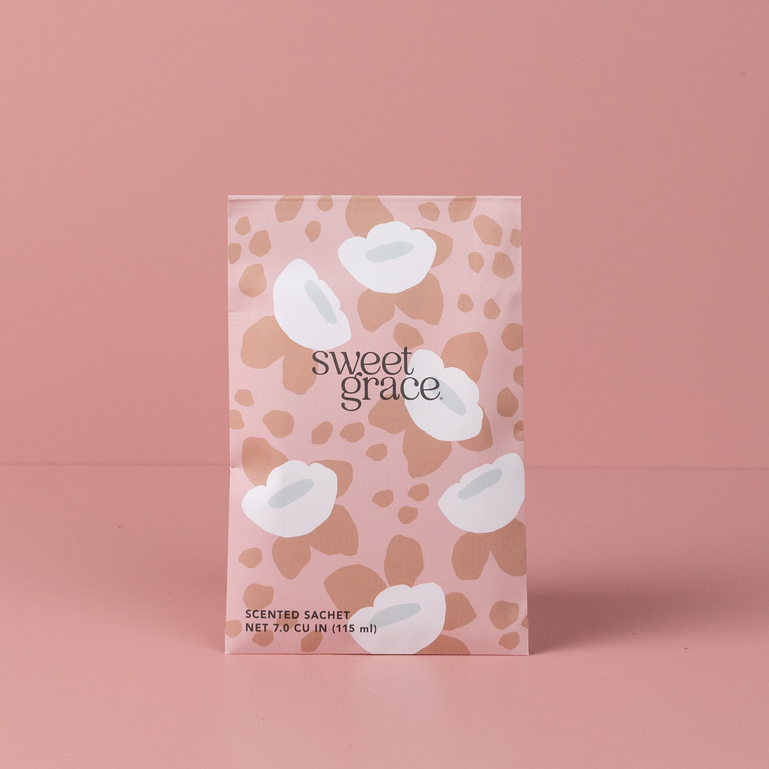 The Bridgewater Candle Company Sweet Grace Modern Flower Sachet stands upright in pink packaging with white abstract flowers and beige spots, labeled SCENTED SACHET NET 7.0 CU IN (115 ml)—ideal for home fragrance lovers.