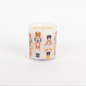 The Bridgewater Candle Sweet Grace Holiday Nutcracker Candle is a white soy-blend candle in a glass jar featuring colorful nutcracker illustrations, shown against a plain white background.