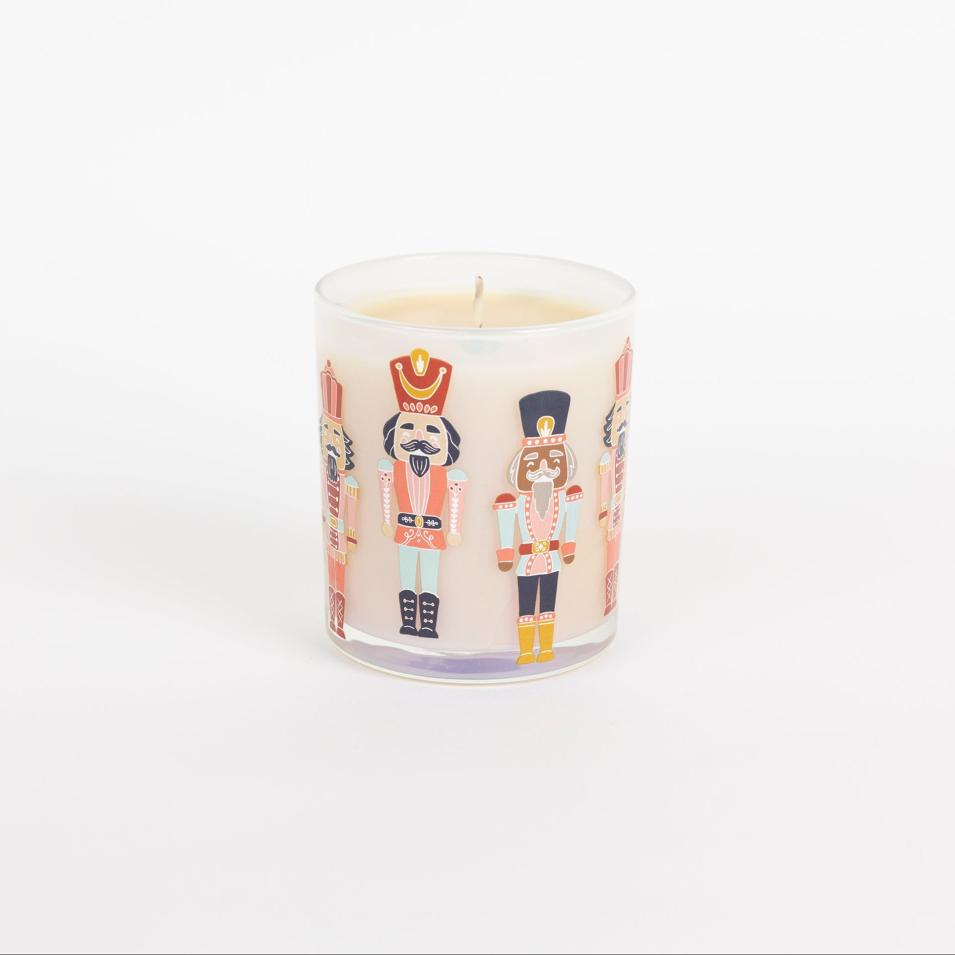 The Bridgewater Candle Sweet Grace Holiday Nutcracker Candle is a white soy-blend candle in a glass jar featuring colorful nutcracker illustrations, shown against a plain white background.