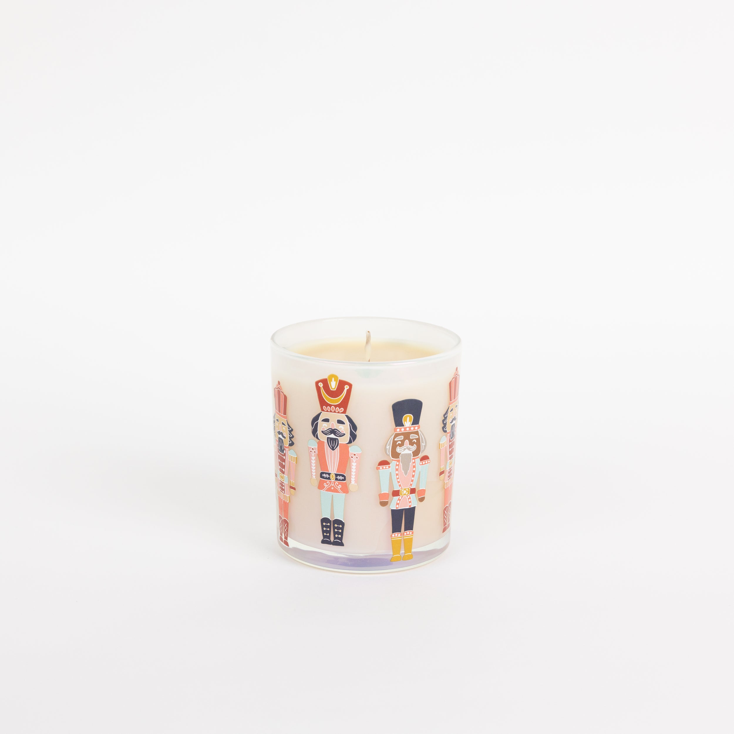 The Bridgewater Candle Sweet Grace Holiday Nutcracker Candle is a white soy-blend candle in a glass jar featuring colorful nutcracker illustrations, shown against a plain white background.