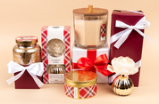 The Comfort & Joy Holiday Mercury Jar Candle gift set by Bridgewater Candle Company features a soy-blend wax candle, flower diffuser, gold jar, tin, and two red gift boxes with white ribbons—all elegantly arranged with festive accents.
