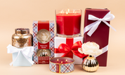 A collection featuring the Bridgewater Candle Companys Welcome Home Mercury Jar Candle, presented in decorative packaging with festive red, gold, and plaid designs, plus white-ribbon boxes—all set against a neutral background.