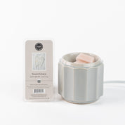 A white wax warmer with a pink soy-blend melt sits beside a Bridgewater Candle Company Sweet Grace Wax Bar, offering stylish, flameless fragrance, all set against a plain white background.