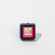 The Let’s Celebrate Auto Vent Clip by Bridgewater Candle Company is a small, square black vent clip with a pink label showing two champagne glasses and the text “Lets Celebrate.”—ideal for adding a festive touch to your car.