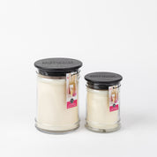 Two Bridgewater Candle Company Lets Celebrate 18oz Large Jar Candles with black lids sit side by side. Each clear glass jar features a product tag with champagne glasses and a pink accent for an elegant touch.