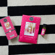 The Lets Celebrate Flameless Bundle by Bridgewater Candle Company, featuring a scented sachet, home fragrance oil, and wax melt, is artfully arranged on a black-and-white checkered rug.