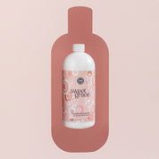 A white bottle of Bridgewater Candle Company’s Sweet Grace 32oz Laundry Detergent, with a pink bubbly label and dark pink silhouette, stands against a light pink background, promising a long-lasting scent.