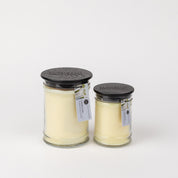 Bridgewater Candle Companys Laundry Line 18oz Large Jar Candle, featuring creamy white soy-blend wax in a glass jar with a black lid and product tag, is displayed alongside another jar against a plain white background.