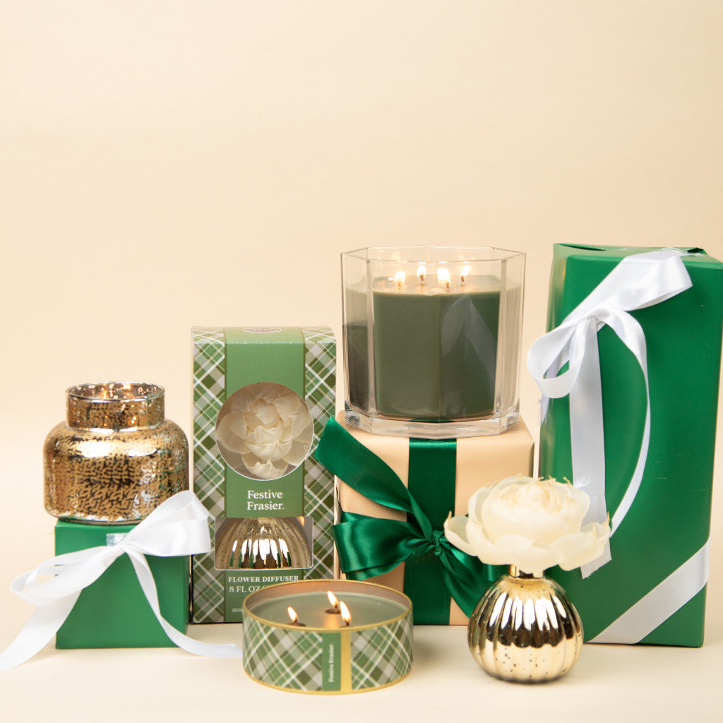 A selection of green and gold holiday gifts, featuring Bridgewater Candle Company's Festive Frasier Holiday Mercury Flower Diffuser and green-wrapped presents with white ribbons, set against a light beige background.