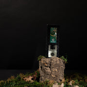 A bottle of Amber & Emerald Reed Diffuser by Bridgewater Candle Company, displayed on tree bark with moss and leaves against a dark backdrop, evokes the fresh, premium fragrance signature to Bridgewater Candle Company.