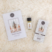 The Festive Frasier Flameless Bundle from Bridgewater Candle Company—home fragrance oil, scented sachet, and soy-blend wax bar—is displayed on a cream rug. Each comes in holiday tree-themed packaging.