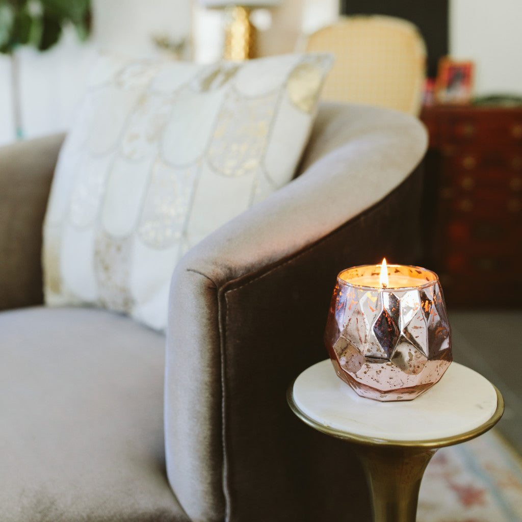 The Sweet Grace Collection Candle #011 by Bridgewater Candle Company, made with soy-blend wax in a faceted glass holder, glows on a table beside a plush armchair, filling your living room with our beloved signature fragrance.