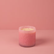 The Bridgewater Candle Sweet Grace Collection Candle #073, a pink marbled three-wick soy-blend candle, rests on a pink surface with a matching pink background.