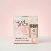 The Sweet Grace Dryer Ball Refill from Bridgewater Candle comes in a pink and white box with circular patterns and includes a 0.33 FL OZ (10 mL) laundry fragrance, ideal for use with wool dryer balls, set against a soft pink background.