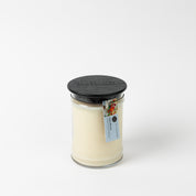 The High Bloom 18oz Large Jar Candle by Bridgewater Candle features creamy soy-blend wax, a black textured lid, and a floral tag, set against a white background. Enjoy its inviting fragrance in any room.