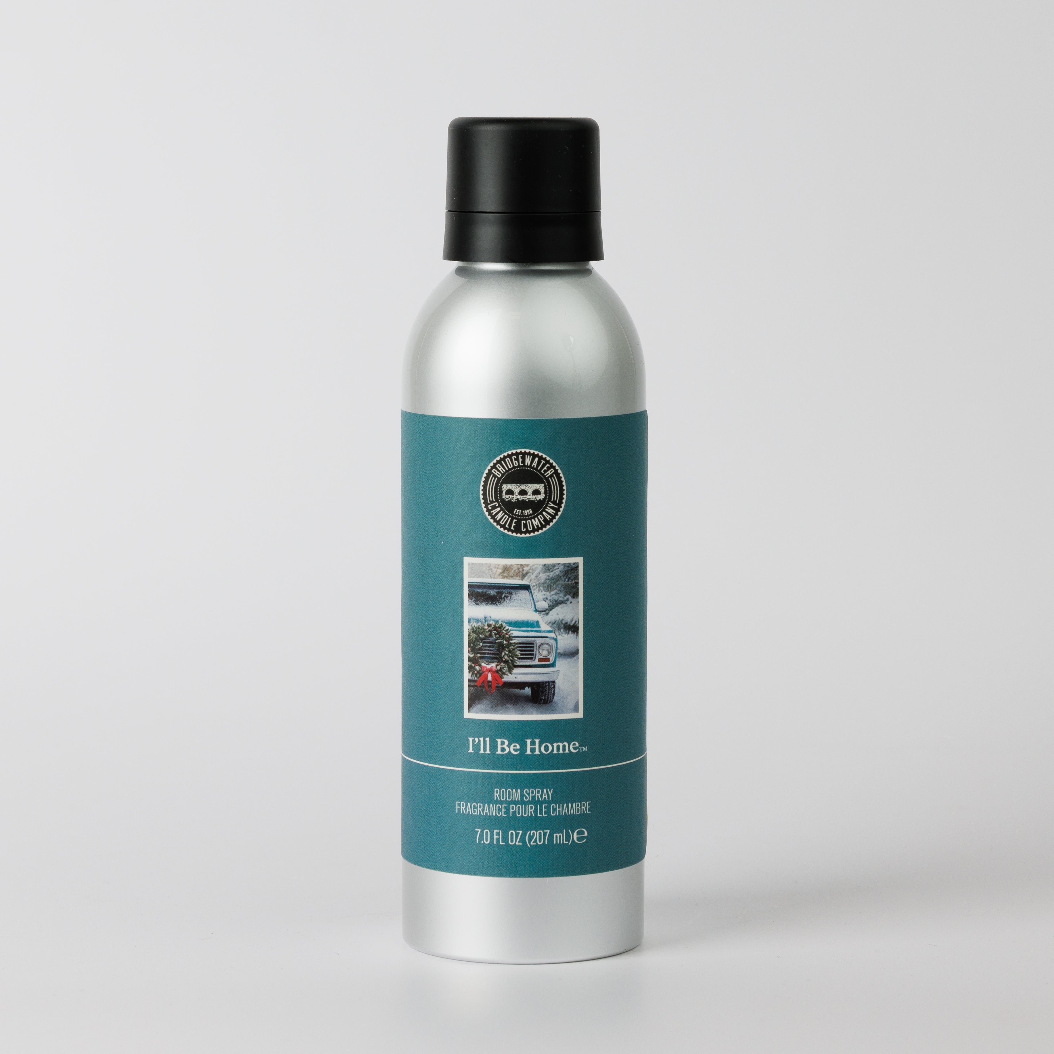 Bridgewater Candle’s “I’ll Be Home” Non-Aerosol Room Spray features a silver bottle with black cap, teal label showing a car with a Christmas tree, and is perfect for eco-friendly holiday fragrance. Size: 7 fl oz (207 mL).