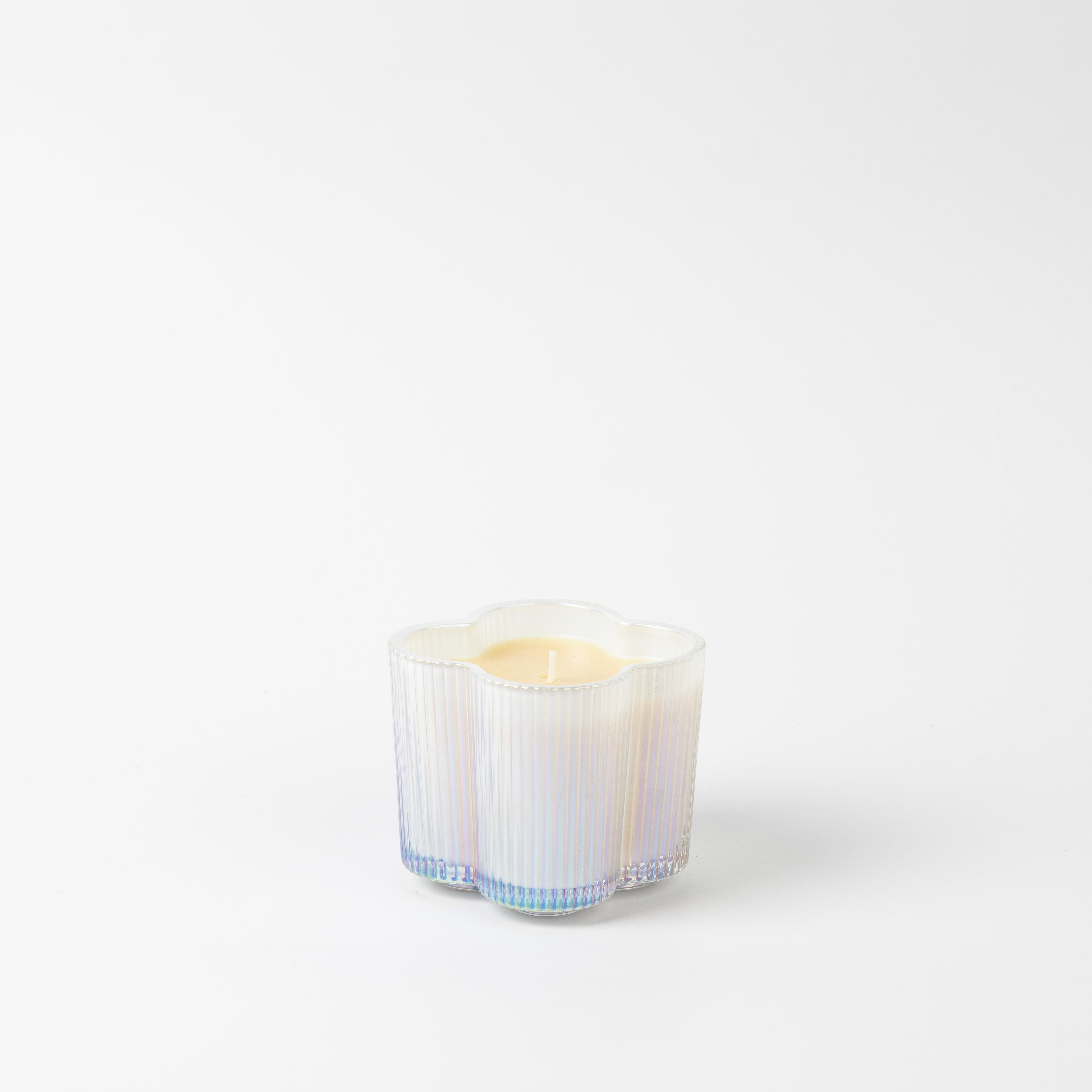 The Bridgewater Candle Sweet Grace Collection Candle #076 is a white flower-shaped soy-blend candle in a translucent glass holder with blue and purple tones, shown against a plain white background.
