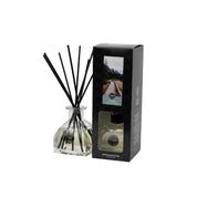 The Solitude Reed Diffuser by Bridgewater Candle features a clear glass bottle with black fiber reeds next to its black box packaging, which displays a mountain road image and product details. The diffuser holds a transparent premium home fragrance liquid.