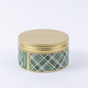 A round gold tin from Bridgewater Candle Company, labeled "Festive Frasier Holiday 3-Wick Tin Candle" in green plaid, features soy-blend wax and is shown against a plain white background.