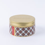 The Bridgewater Candle Company Christmas Bliss Holiday 3-Wick Tin Candle features a round tin with a gold embossed lid and plaid red, green, and white sides labeled "Christmas Bliss." Filled with festive soy-blend wax for holiday cheer.