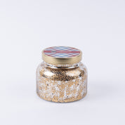 The Welcome Home Mercury Jar Candle by Bridgewater Candle Company features a gold and white speckled glass jar with a plaid-accented gold lid. This soy-blend candle brings premium home fragrance to any space.
