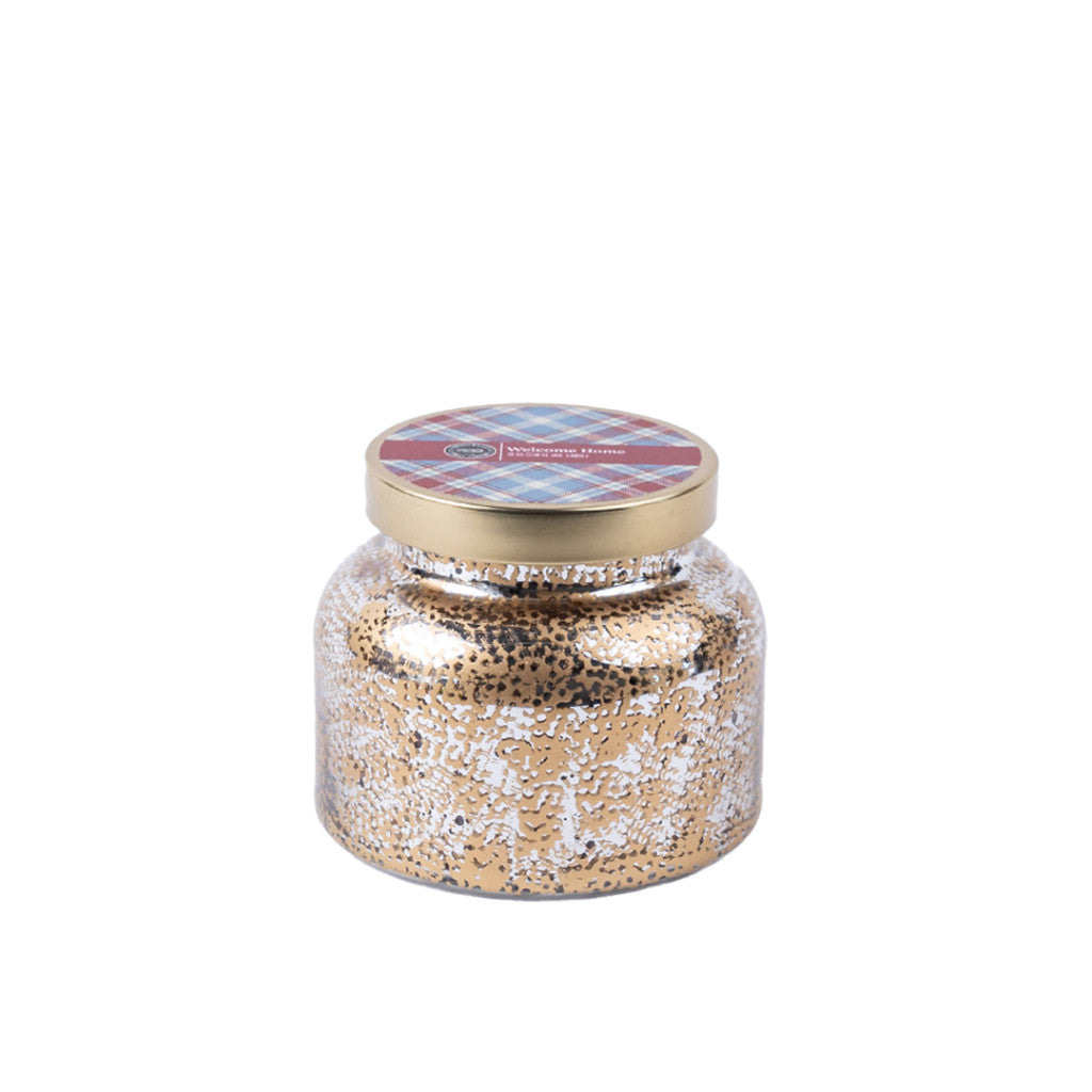 The Welcome Home Mercury Jar Candle by Bridgewater Candle Company comes in a gold and silver speckled glass jar with a gold lid, topped with red and blue plaid, and is filled with soy-blend wax.
