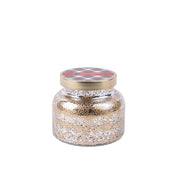The Christmas Bliss Holiday Mercury Jar Candle by Bridgewater Candle Company features a gold metallic lid with a red and black patterned label and is filled with gold and silver glitter—perfect for festive décor. Displayed against a plain white background.