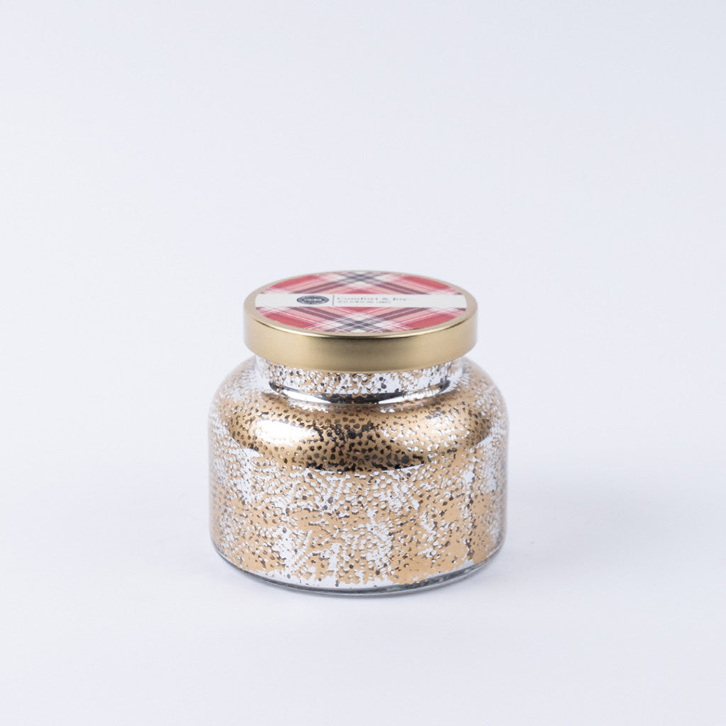 The Bridgewater Candle Company Comfort & Joy Holiday Mercury Jar Candle features premium soy-blend wax in a decorative glass jar with gold and white speckles, a gold lid with pink and gray plaid, and a small label—all set against a white background.